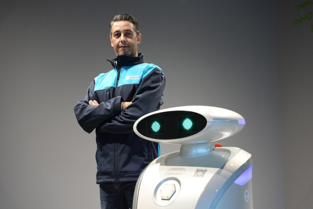 Bidvets Noonan cleaning operative posing beside a cobot used for cleaning services