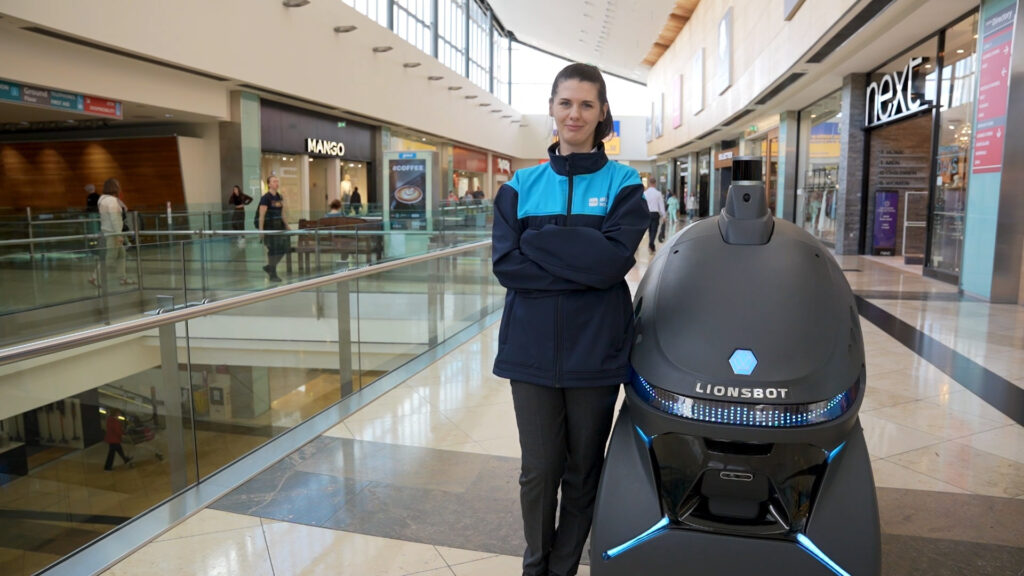 cleaning operative posing beside a cobot in a retail environment